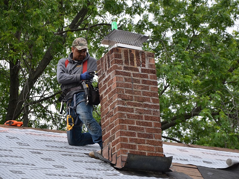 the kingdom builders roofer working near brick chimney