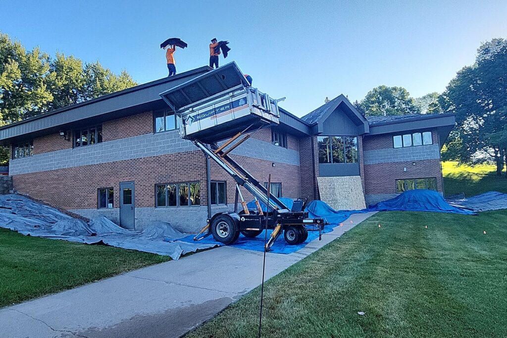 roofers throwing old materials into equipter