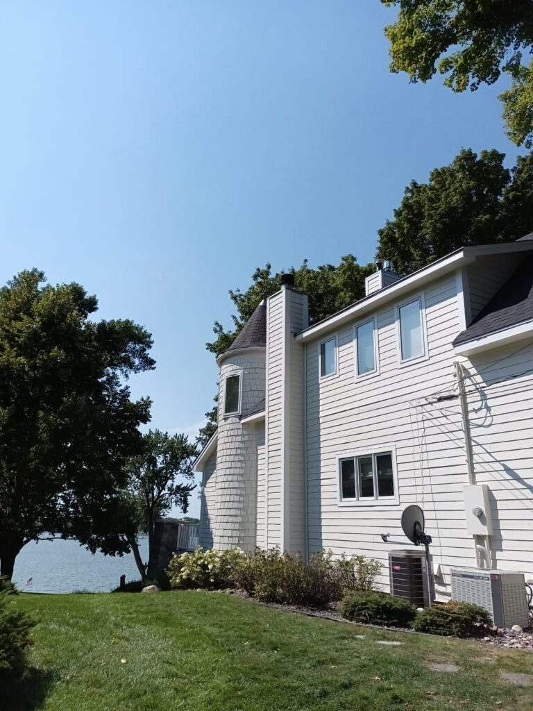 side of home with turret and lake view